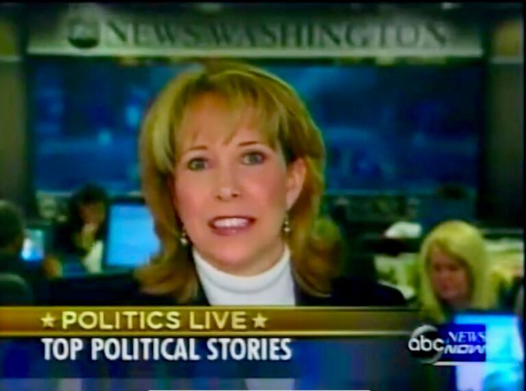 Image of an old ABC News broadcast segment, showing Loretta's head and neck as she appears to be in the middle of speaking; below her head is a banner across the bottom of the broadcast that reads "Politics Live: Top Political Stories."