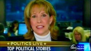 Image of an old ABC News broadcast segment, showing Loretta's head and neck as she appears to be in the middle of speaking; below her head is a banner across the bottom of the broadcast that reads "Politics Live: Top Political Stories."